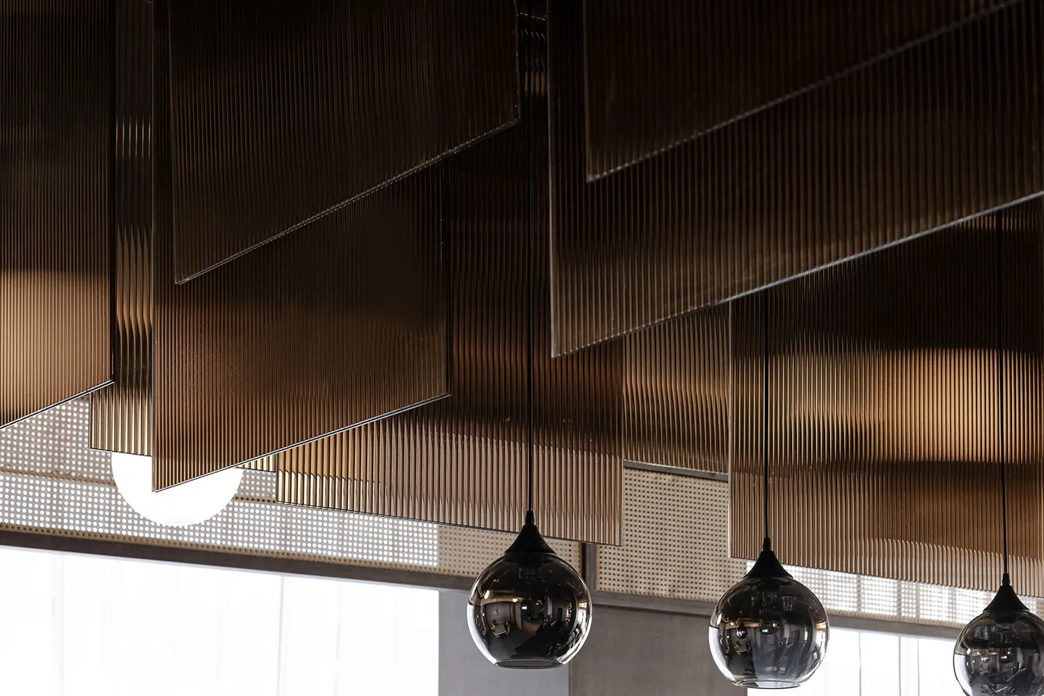 A modern restaurant interior featuring metallic textured panels and hanging light fixtures.