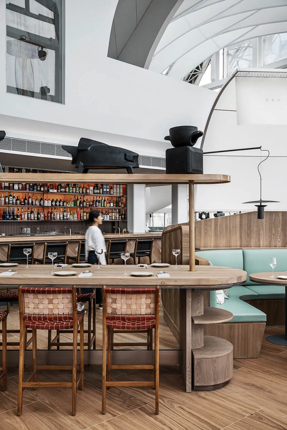 工業風餐廳室內,配有木製餐桌椅與皮革座椅、金屬燈具及吧檯