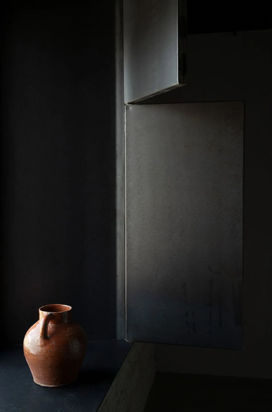 A minimalist interior design featuring metallic shadows on dark, textured walls.