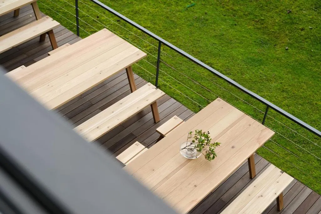Modern outdoor furniture collection consisting of multiple tables and benches made of light-colored wood with a minimalist de