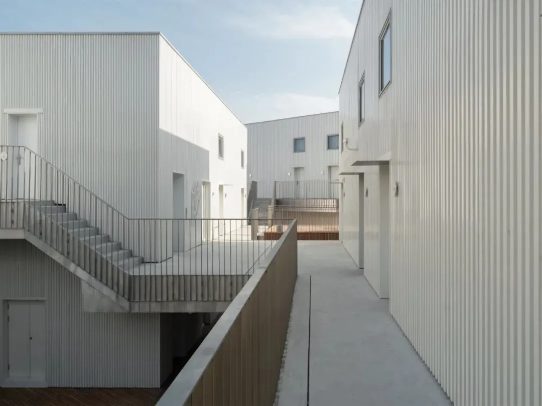 Modern residential buildings with metal cladding and exterior walkways.