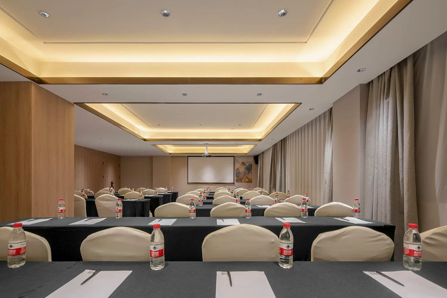 Empty conference room with tables, chairs, and water bottles arranged in rows.