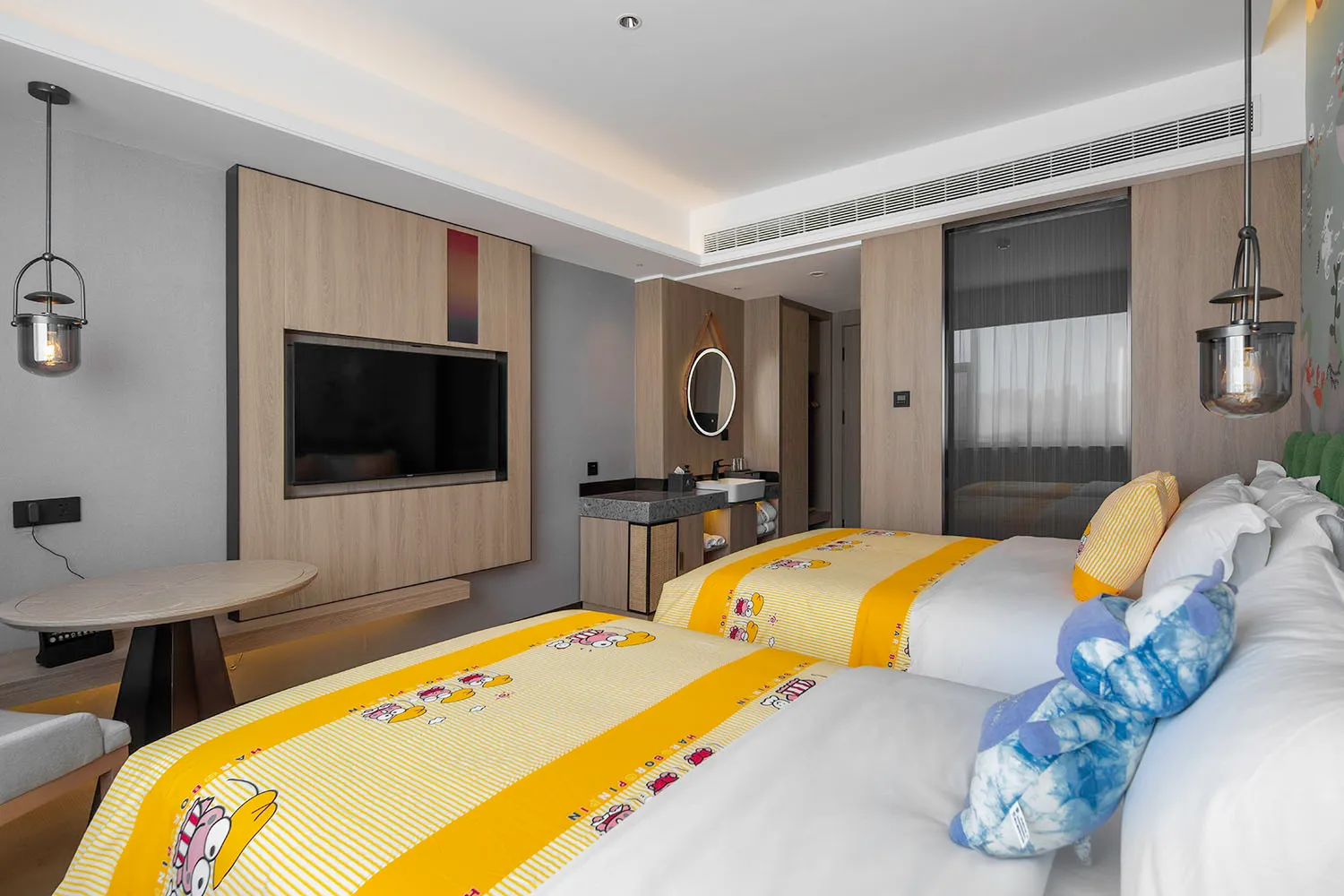 A modern bedroom with a wooden wall, a yellow bedspread, and a flat-screen TV mounted on the wall.