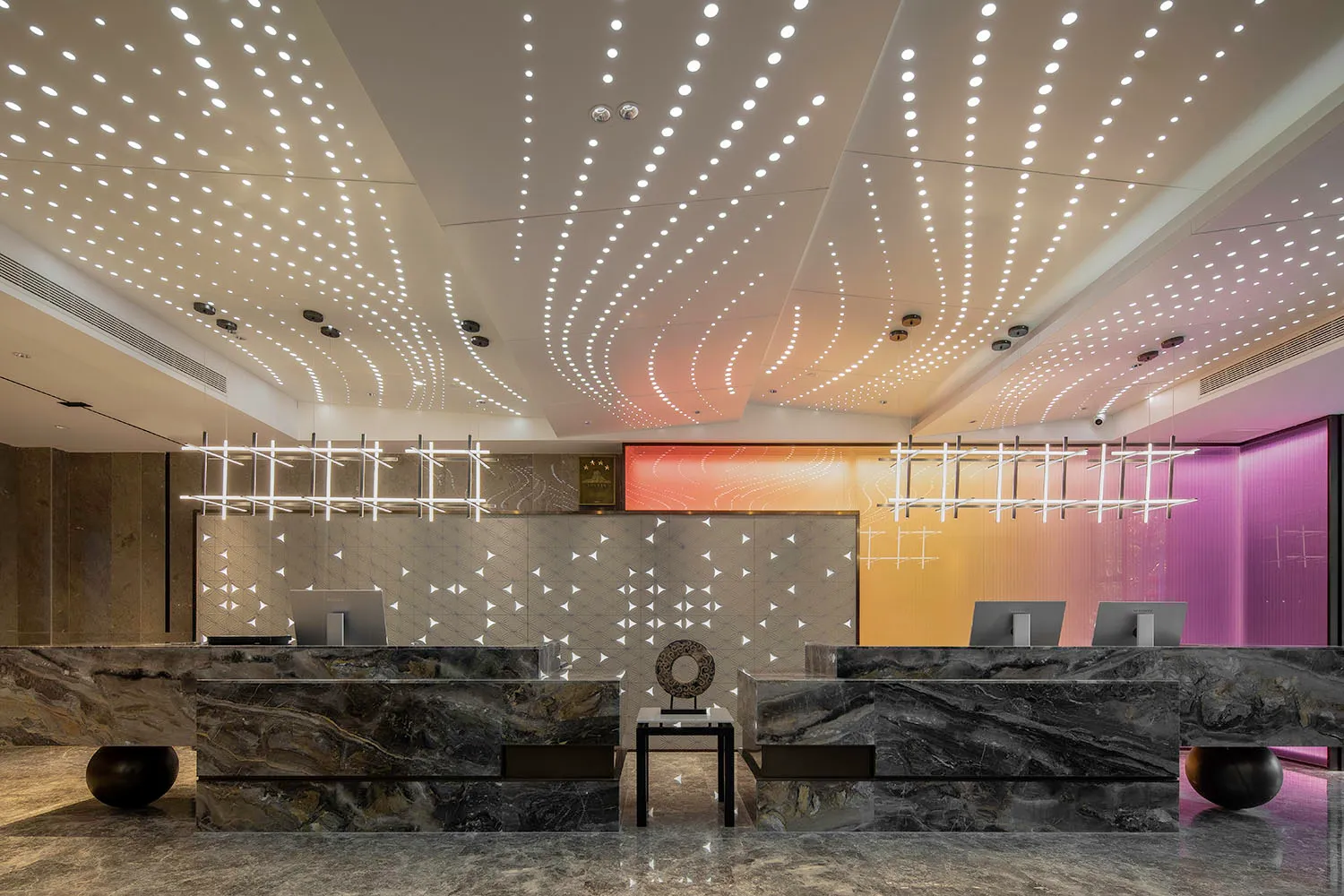 A modern hotel reception desk made of marble, featuring intricate lighting and a sleek design.