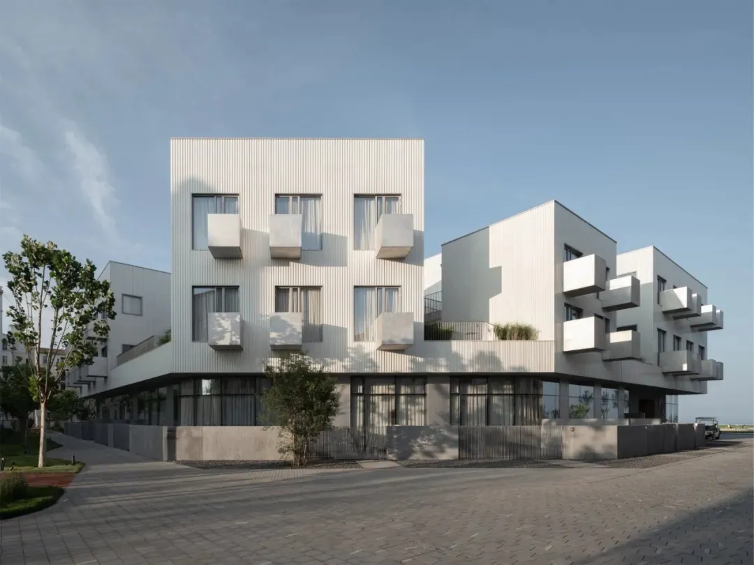 A modern residential apartment building with white-rendered concrete exterior.