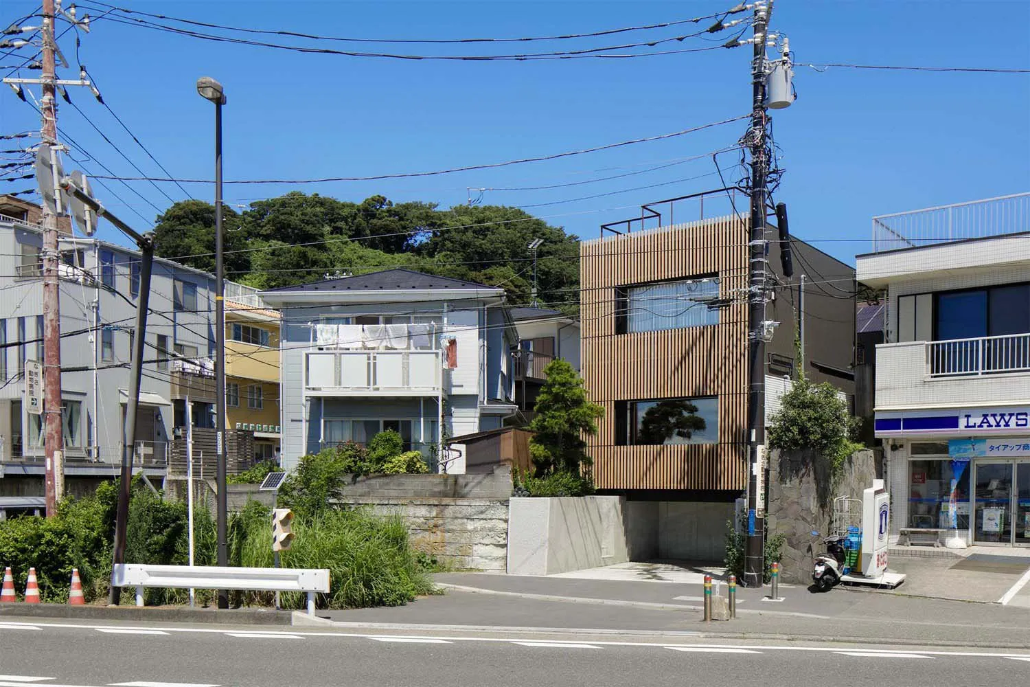一棟現代建築採用木質板材、混凝土與玻璃立面，坐落於有電線與路燈的街道上。