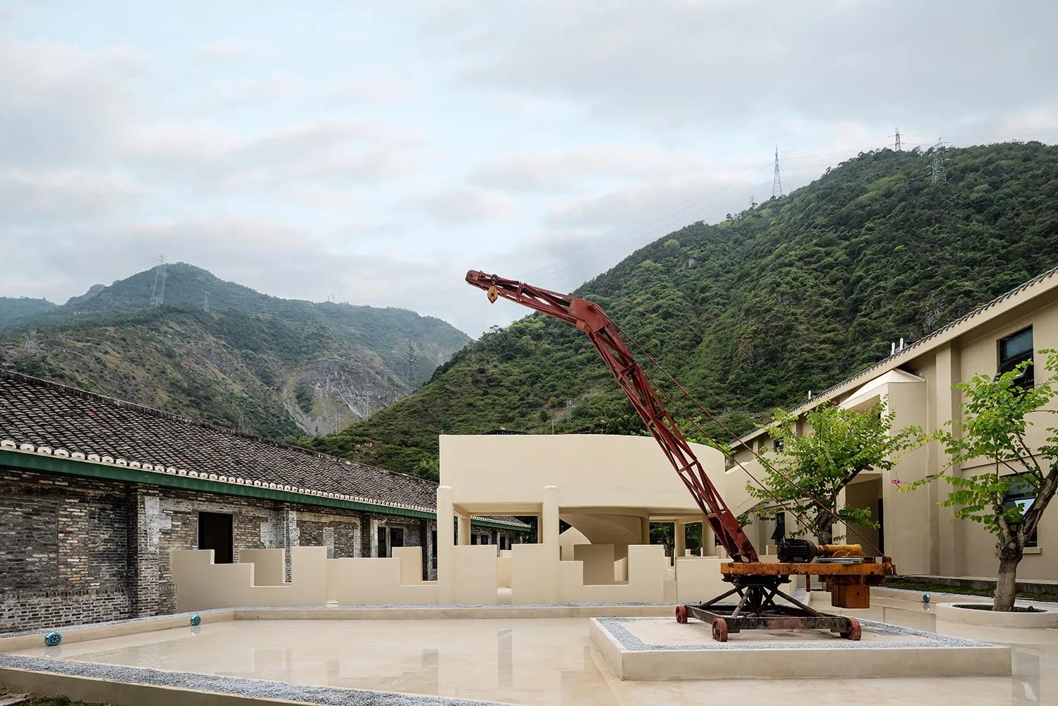 A red crane arm against a backdrop of mountains and buildings under construction