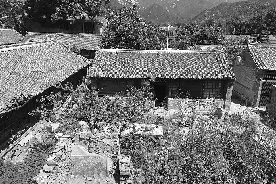 A courtyard with tiled roofs surrounded by traditional buildings and greenery.