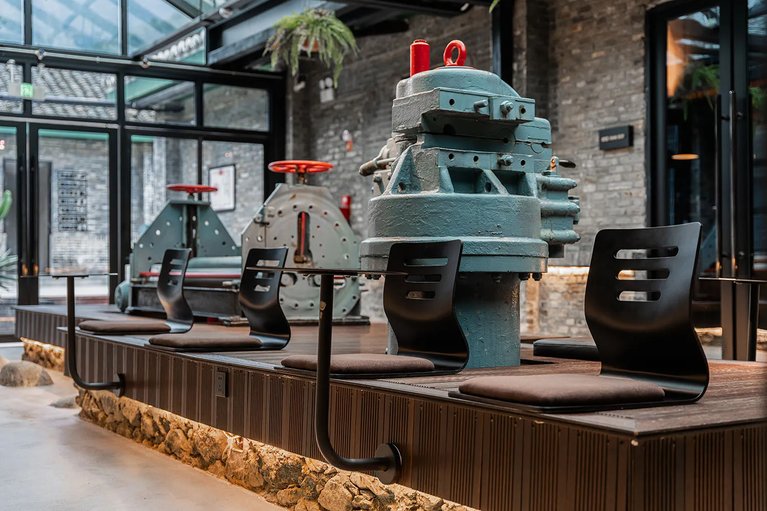 Industrial-style cafe interior with metal machinery and concrete seating.