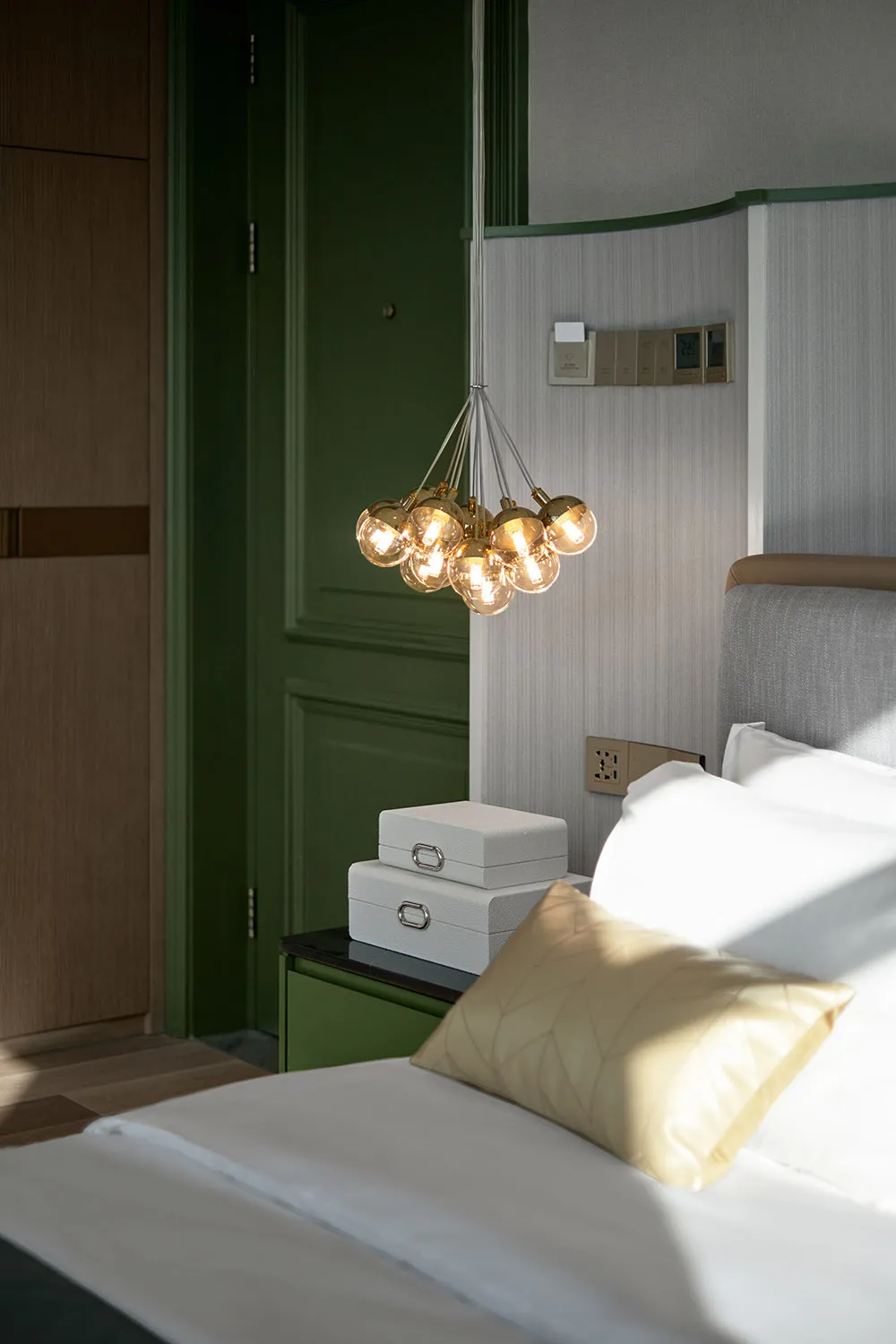 A minimalist bedroom featuring a modern light fixture and textured bedding.