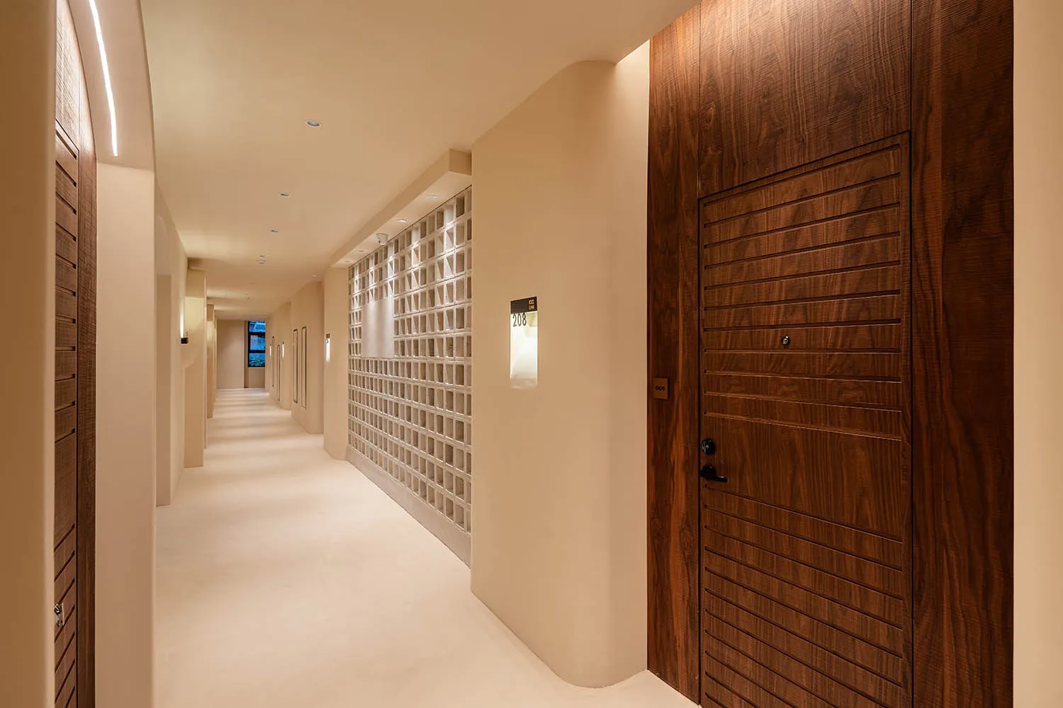 A minimalist designed corridor with wooden doors and a concrete wall, featuring a warm lighting setup.