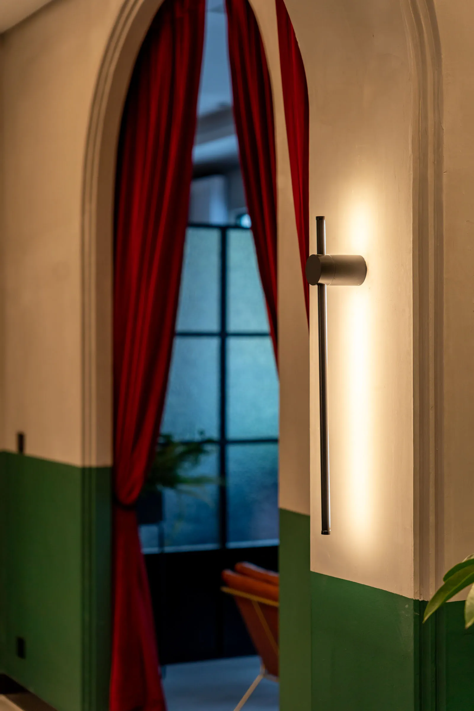 Modern architecture with white and green colors, red curtains, and a wall-mounted light fixture.