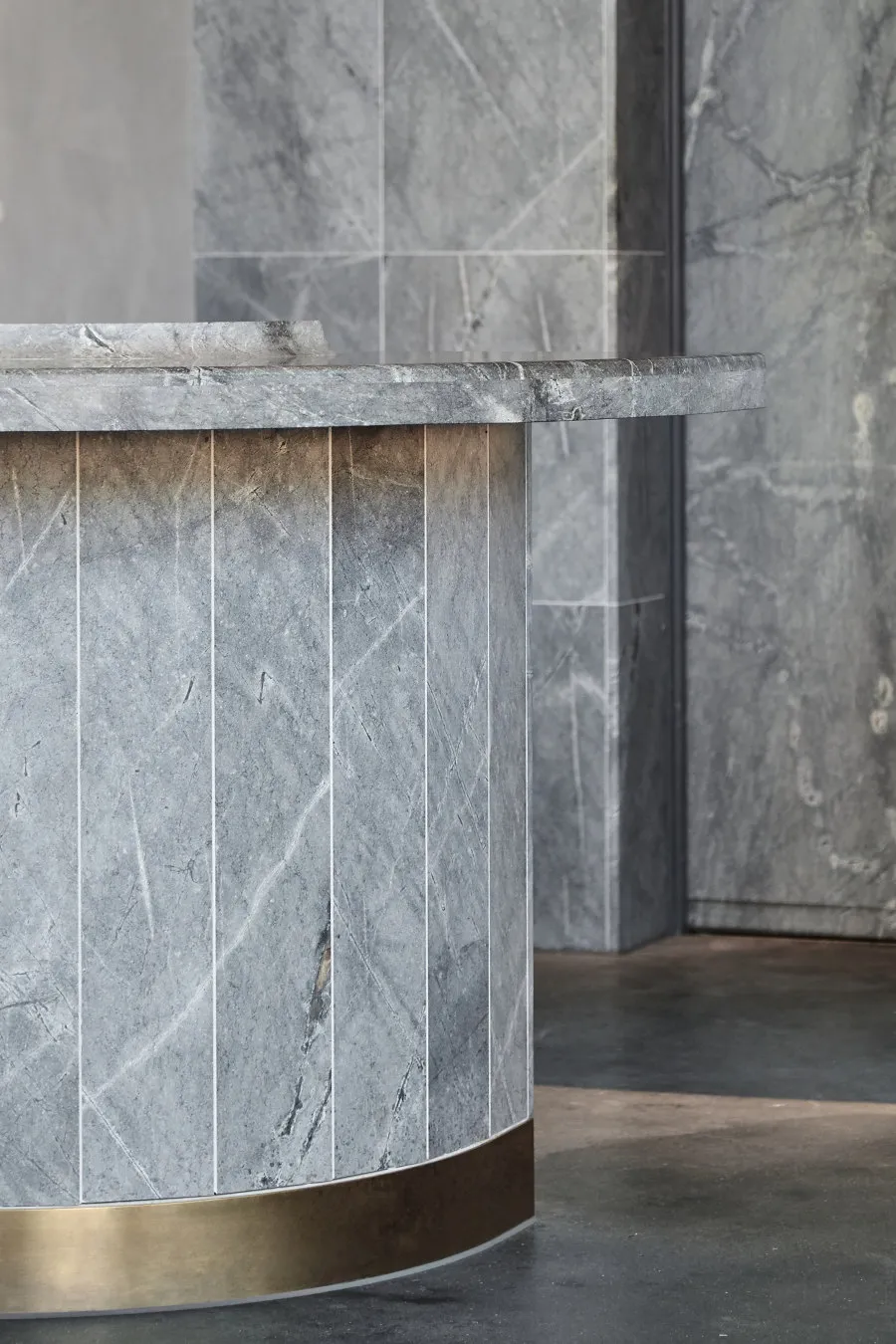A modern marble reception counter with a brass base in a contemporary interior design setting.