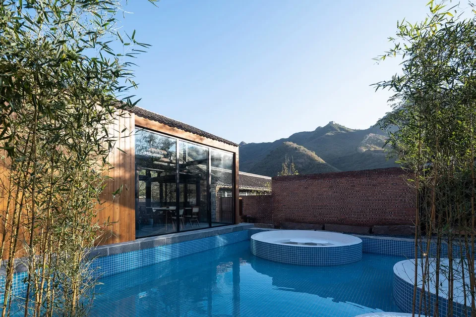 Modern minimalist residential patio featuring sleek glass walls overlooking mountains.