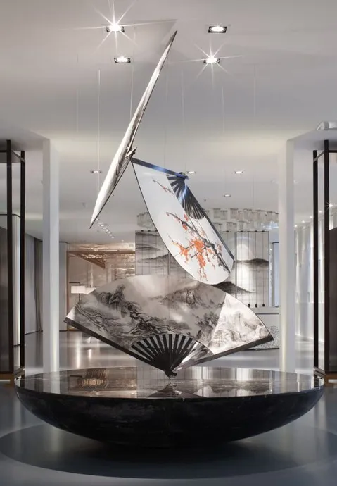A minimalist modern office space featuring three metal art pieces hanging from the ceiling.