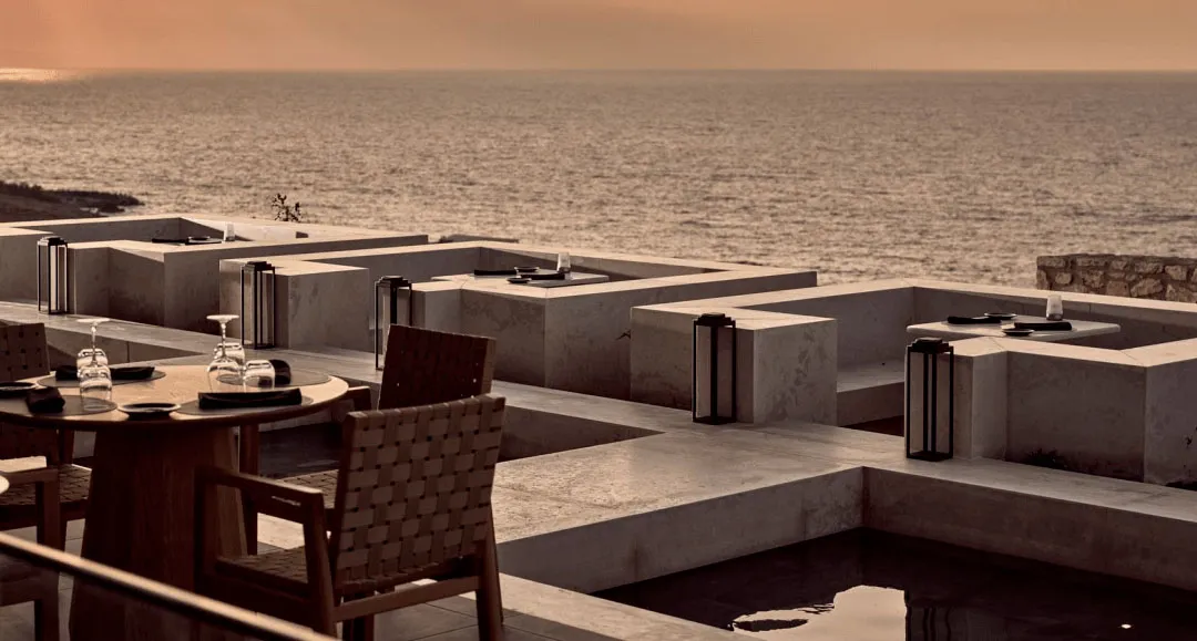 A modern patio with concrete furniture and a view of the ocean.