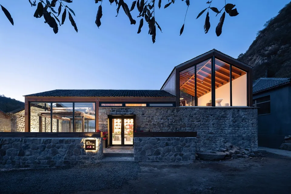 A modern residential building with stone exterior and large glass windows.