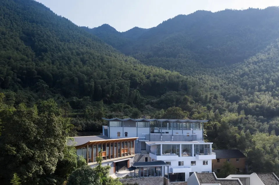 現代住宅玻璃牆面,眺望翠綠山丘與山巒景色。