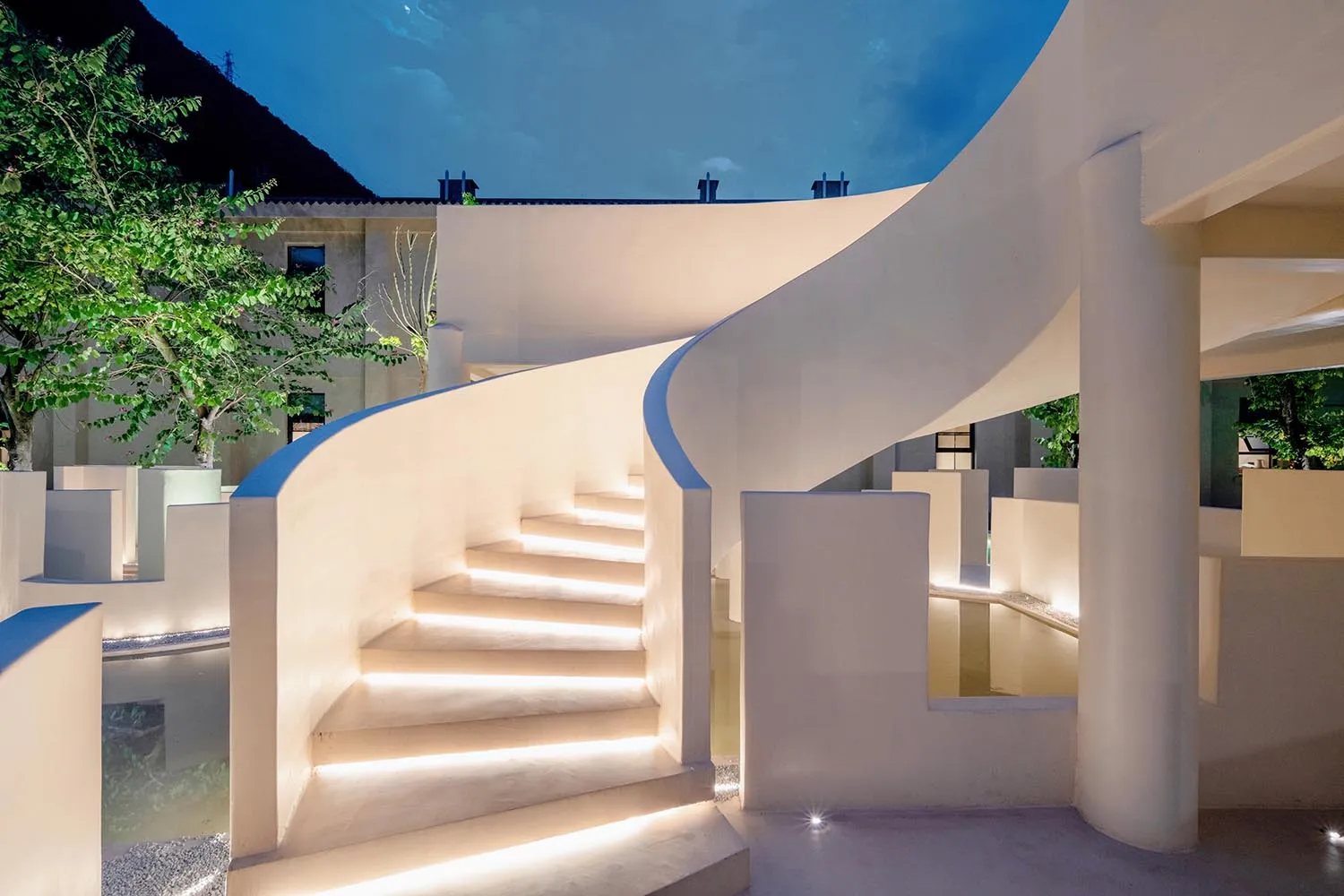 A modern sculpture space with illuminated elements and a curved staircase.