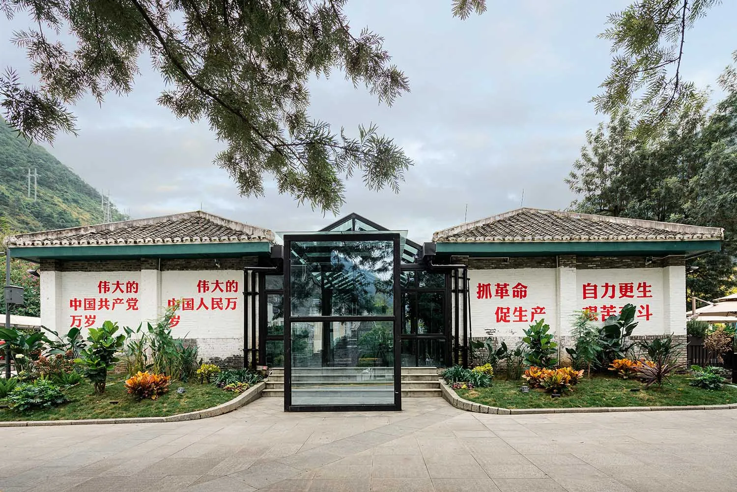 傳統中式建築外觀,入口為玻璃門,搭配綠色植物與牆面紅色標語。