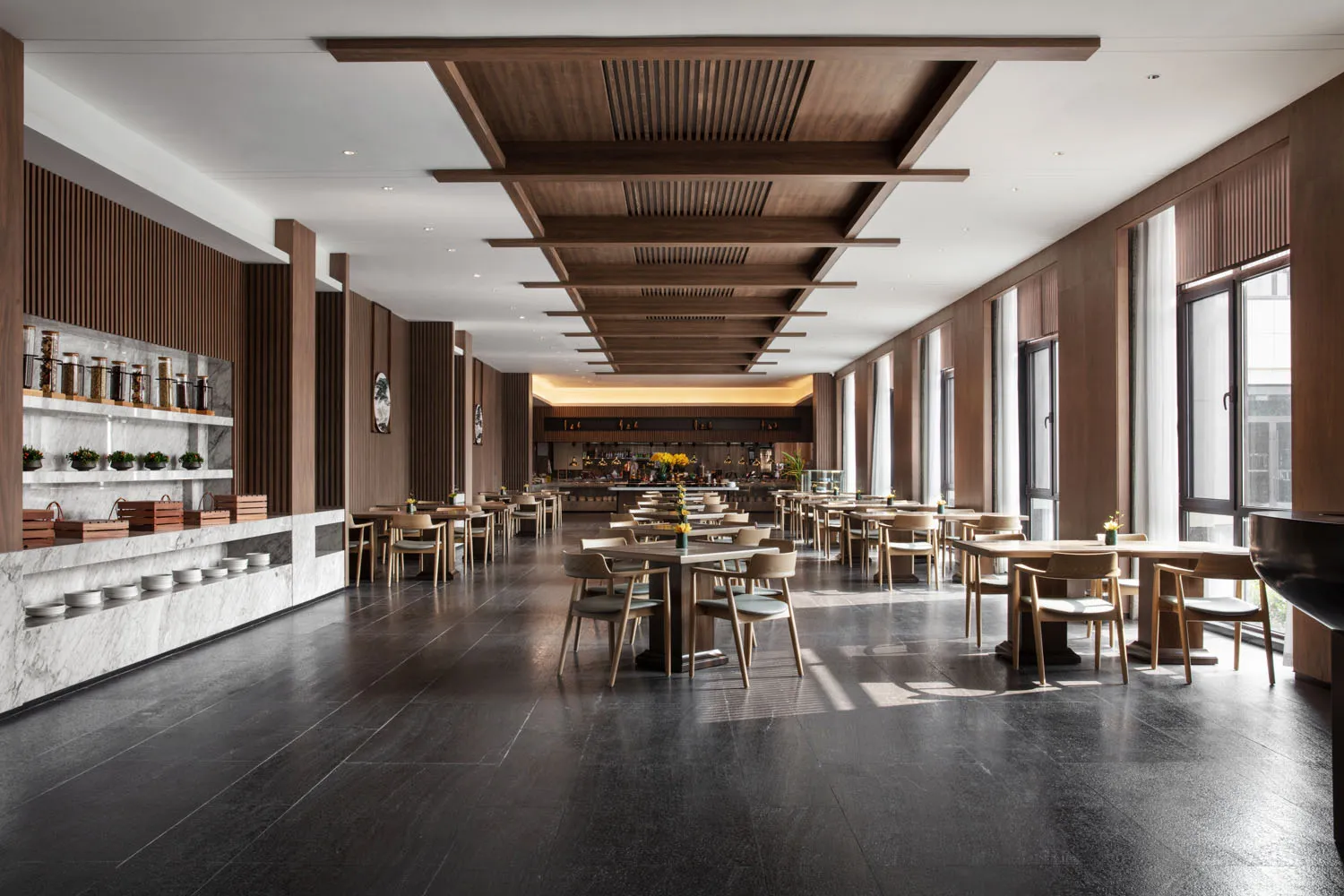 Industrial-style restaurant interior with marble countertops, wooden tables, and metallic bar.