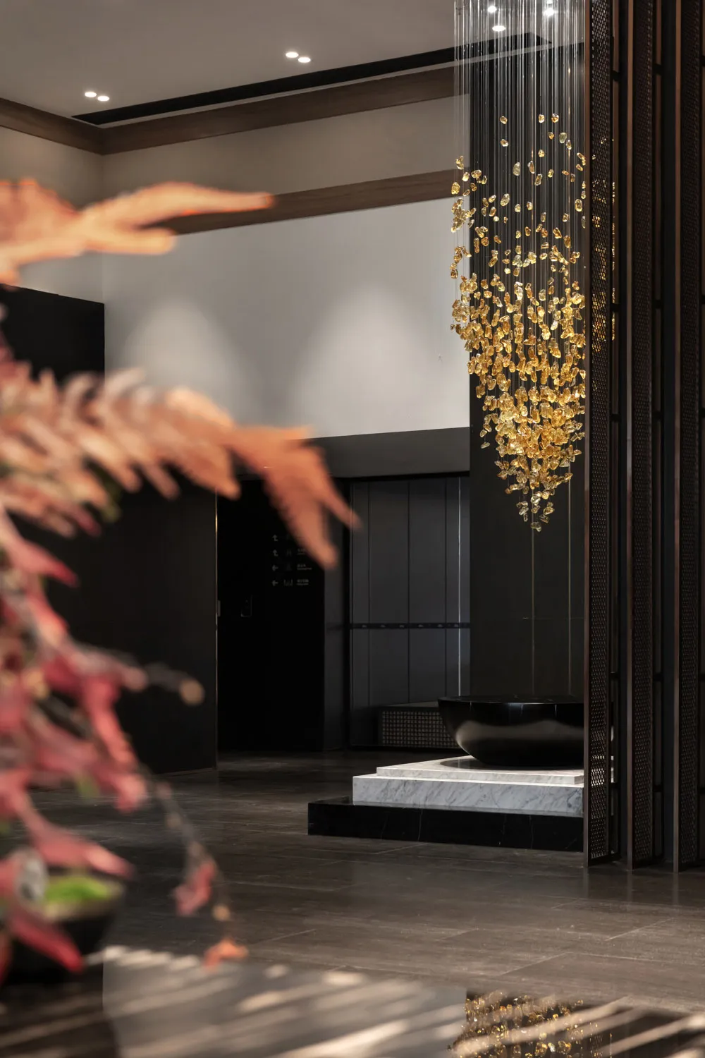 A modern hotel lobby interior featuring a metallic pendant lighting fixture.