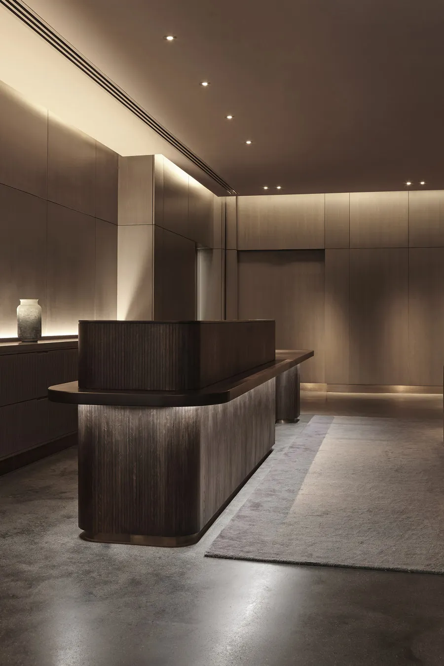 A modern interior reception area featuring a wooden desk and lighting.