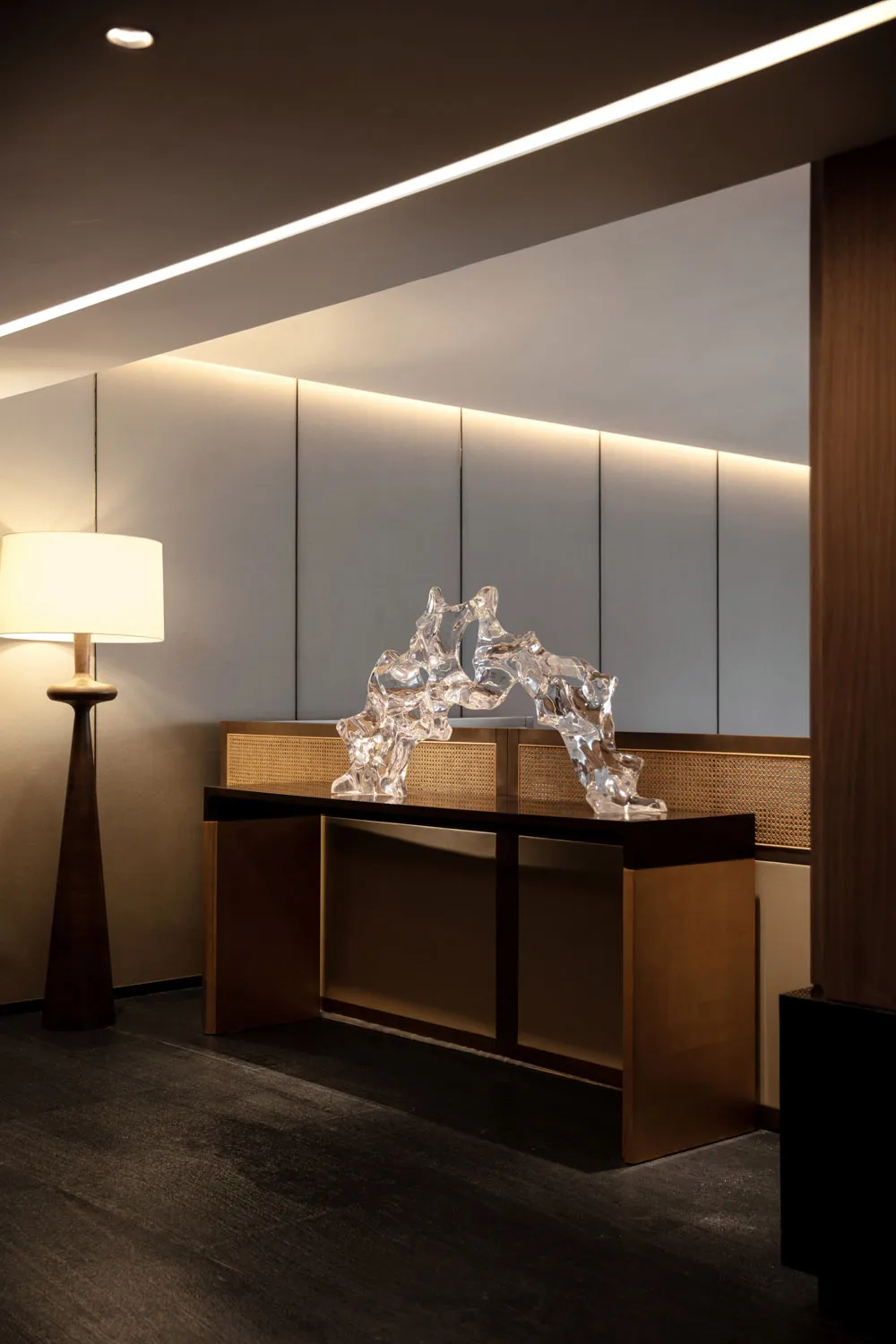 A modern lobby featuring a glass sculpture centered on a wooden side table.