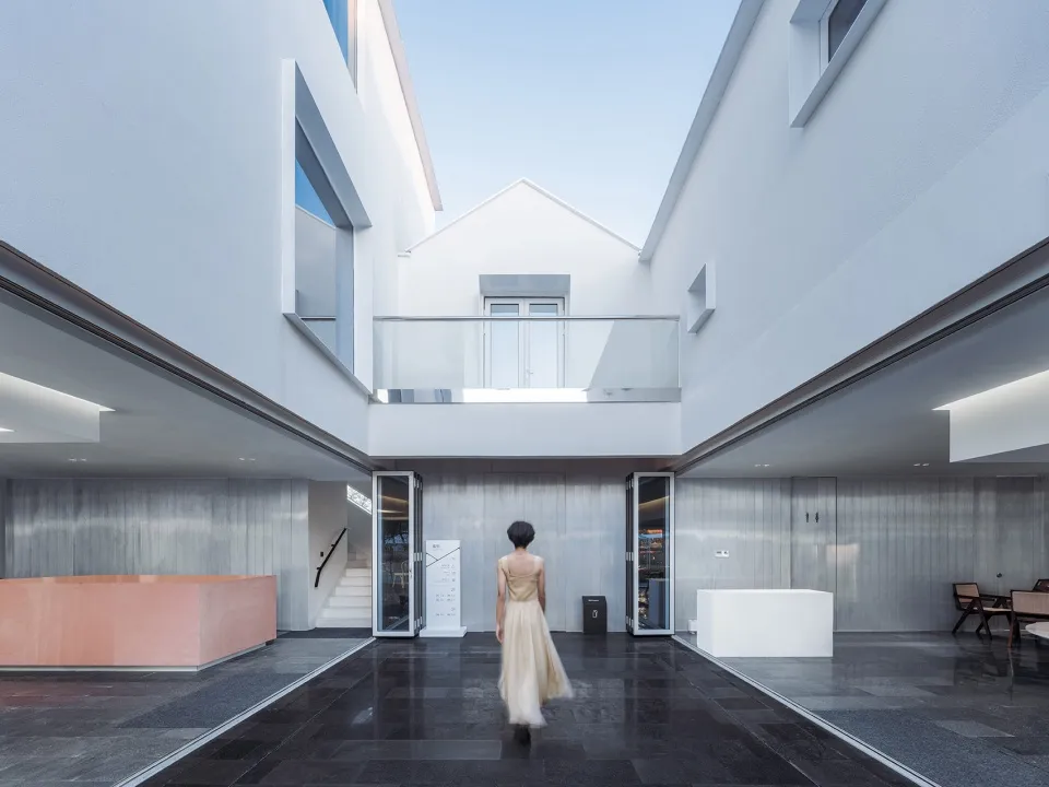 A modern interior space with glass walls, concrete floors, and metallic accents.