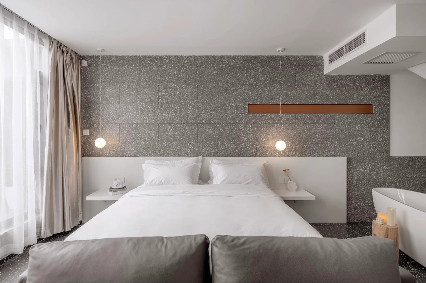 A modern minimalist bedroom featuring a grey concrete wall with floating nightstands and a white bed.