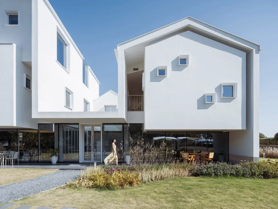 A modern residential exterior with white walls and large windows.