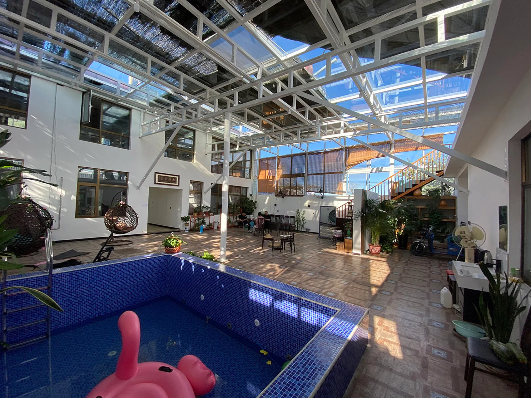 A modern, spacious lounge area featuring concrete flooring and a poolside seating area with a pink flamingo float.