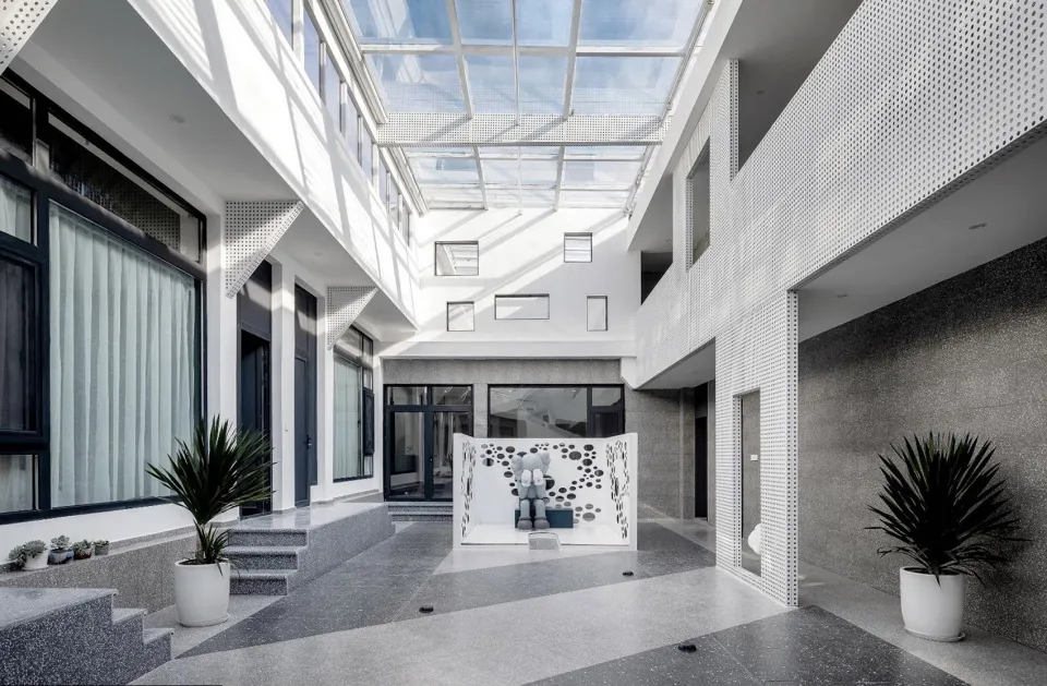 A minimalist modern residential interior with white ceramic tiles, granite walls, and large glass windows.