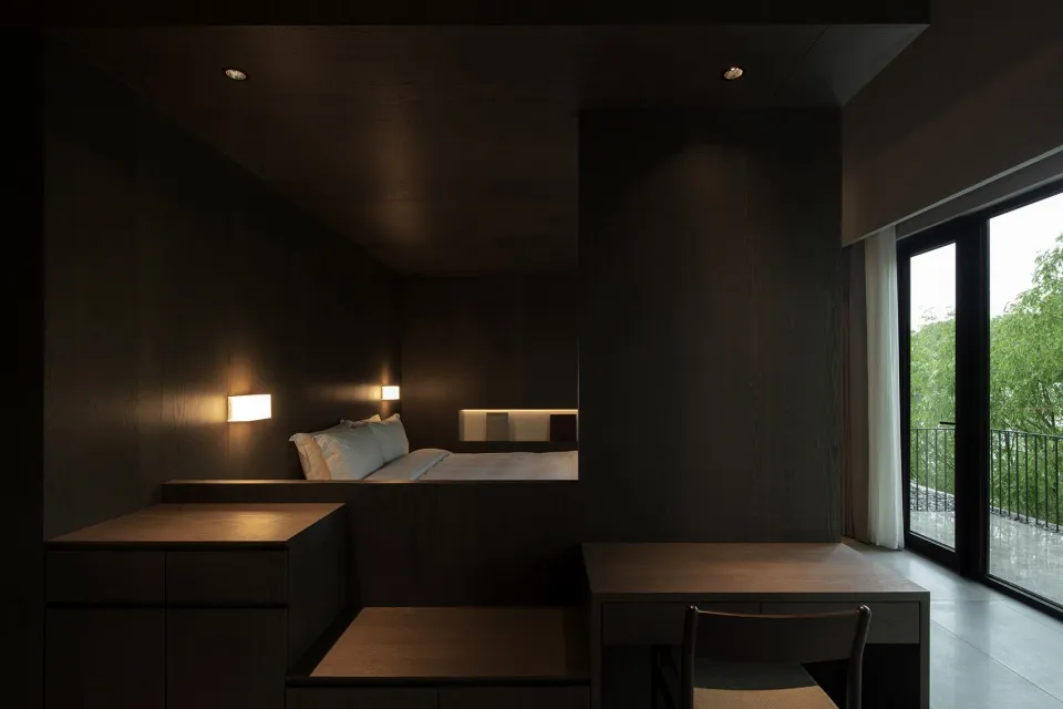A modern, minimalist bedroom with dark wood accents and neutral color tones.