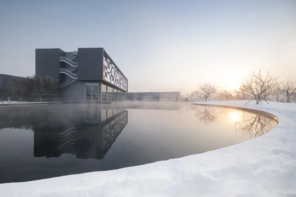 Modern architectural building with snow-covered surroundings reflected in calm water