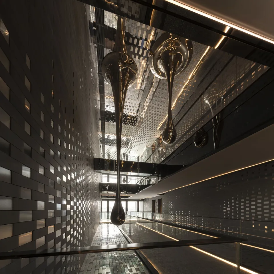 Modern hotel corridor featuring metallic tiles and steel elements.
