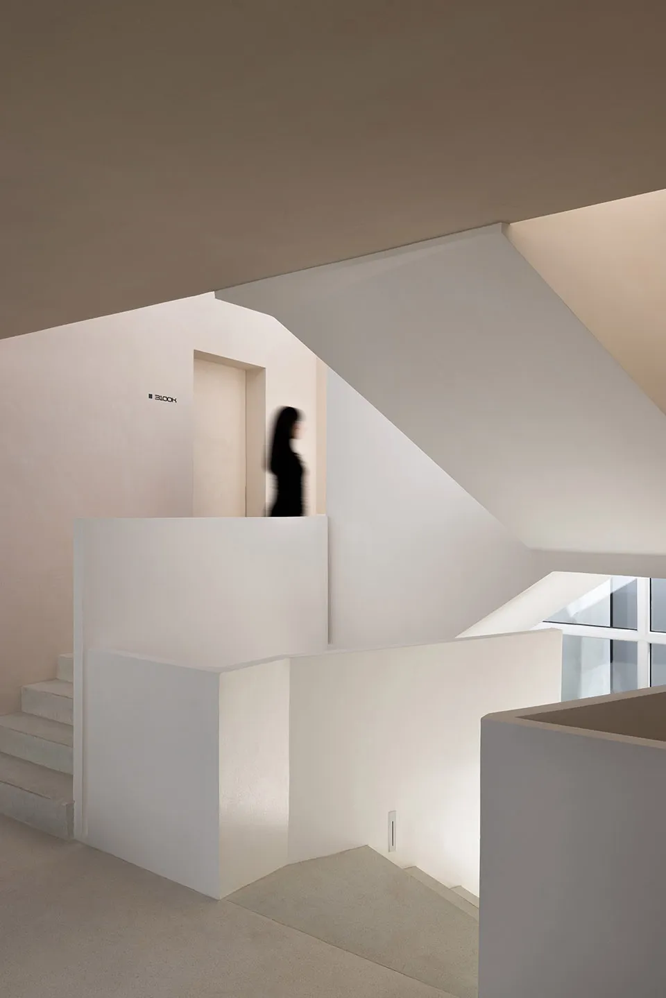 A minimalist interior with concrete walls and a white staircase.