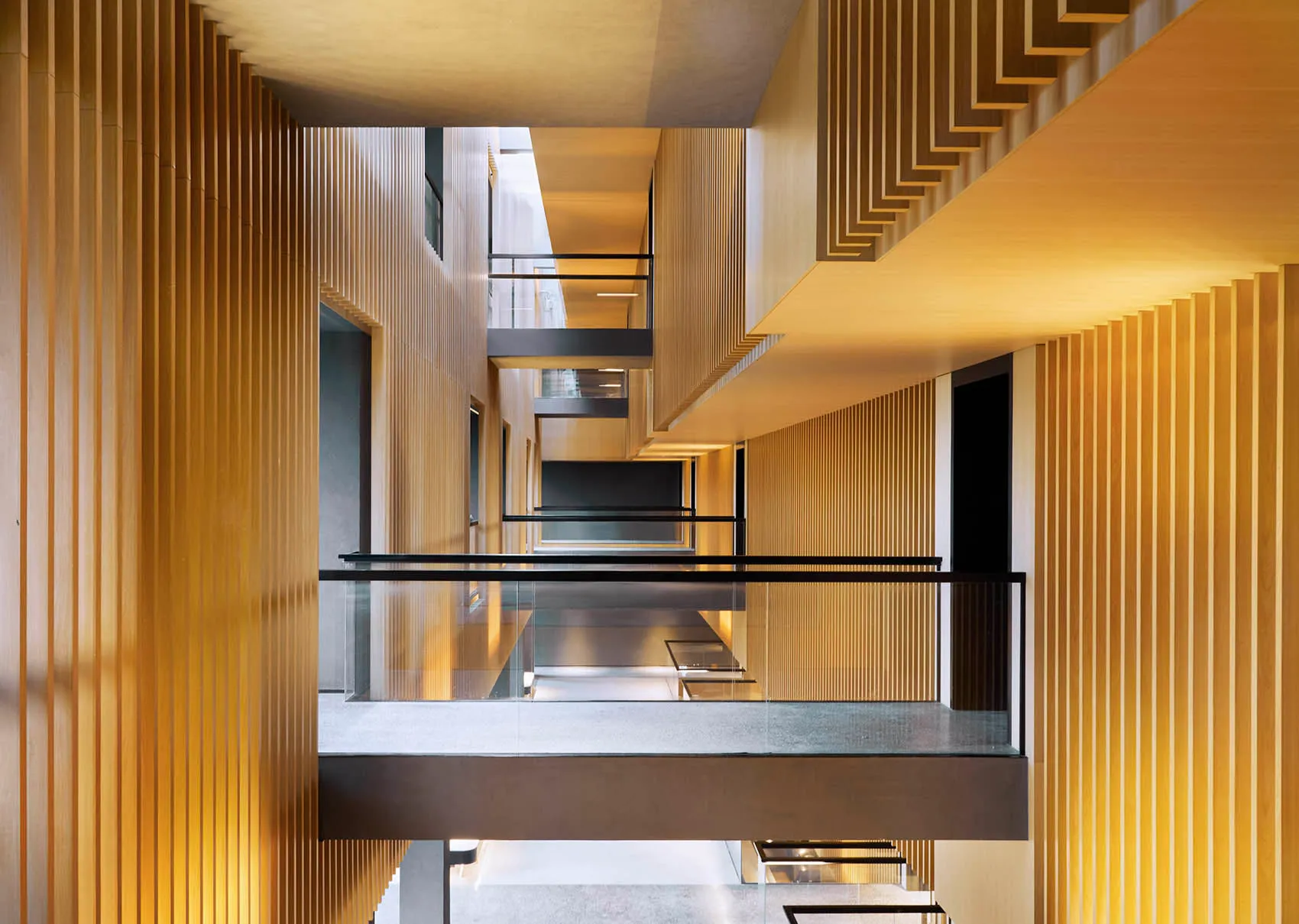 A modern interior corridor featuring wooden walls and lighting.