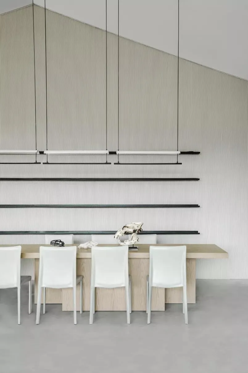 Modern dining room with white chairs and a wooden table.