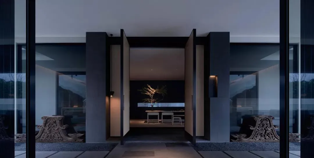 Modern entryway with glass walls and concrete walls featuring minimalistic design elements and lighting.