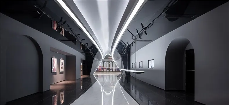 An expansive modern art gallery with glass walls, steel elements, and minimalist lighting.