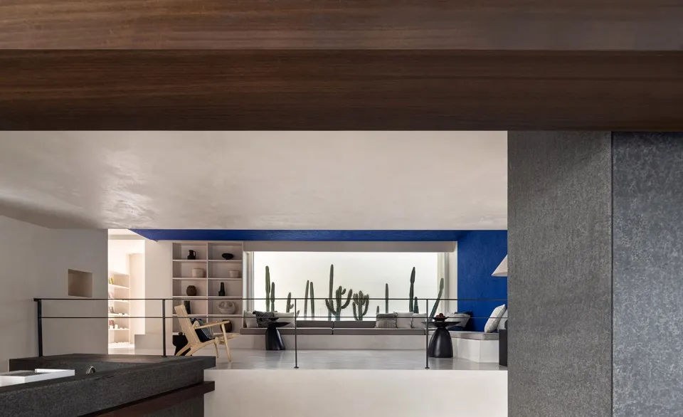 Modern residential interior with concrete walls and wooden ceiling beams.