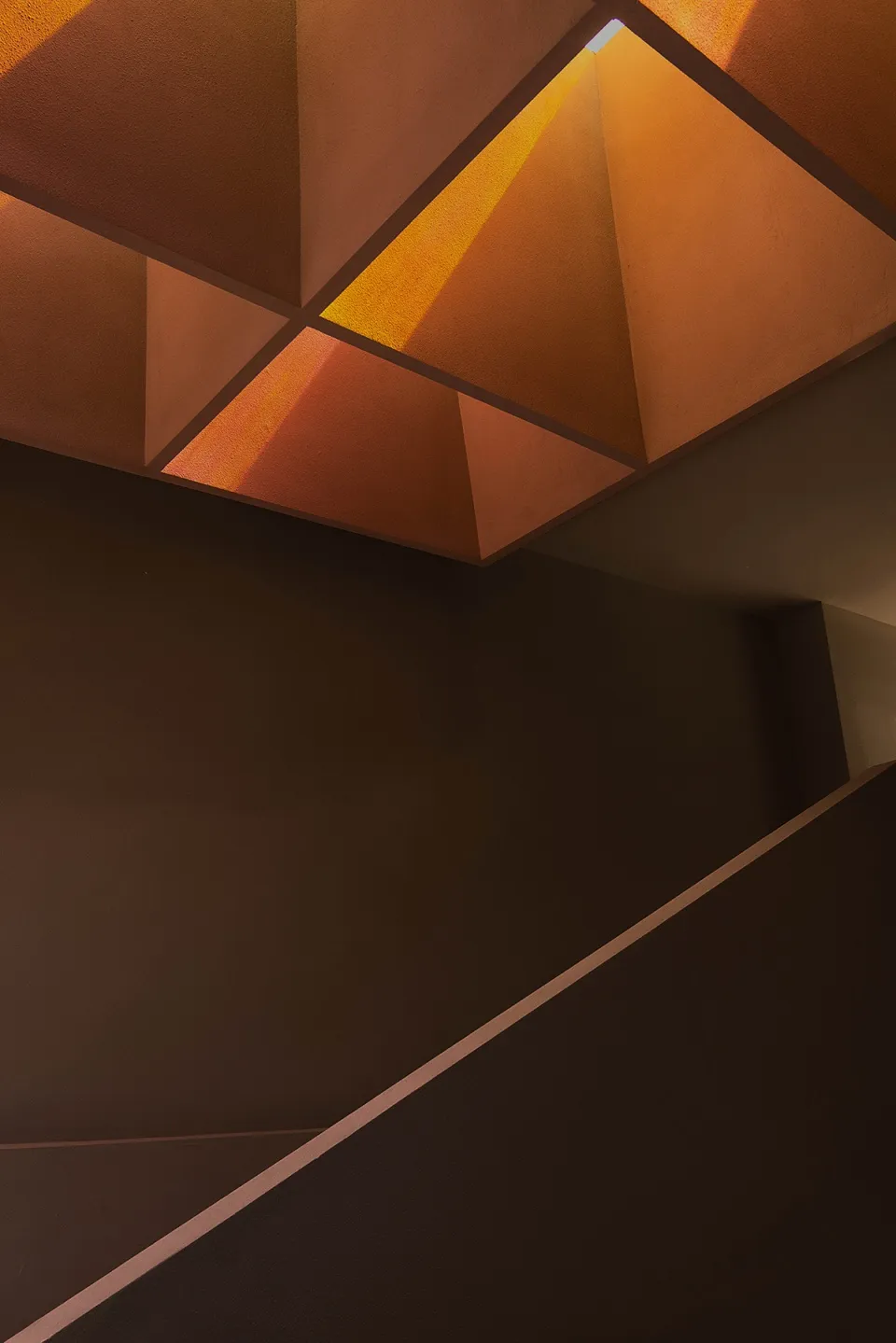 Modern concrete staircase with geometric design and orange lighting
