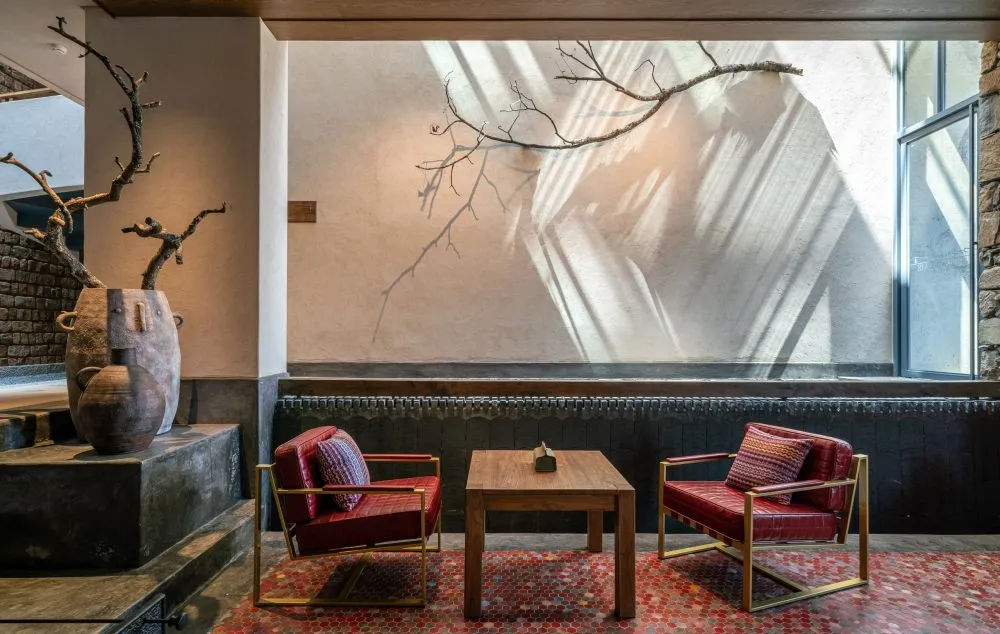 An industrial-style reception space with red leather chairs and gold metal accents.