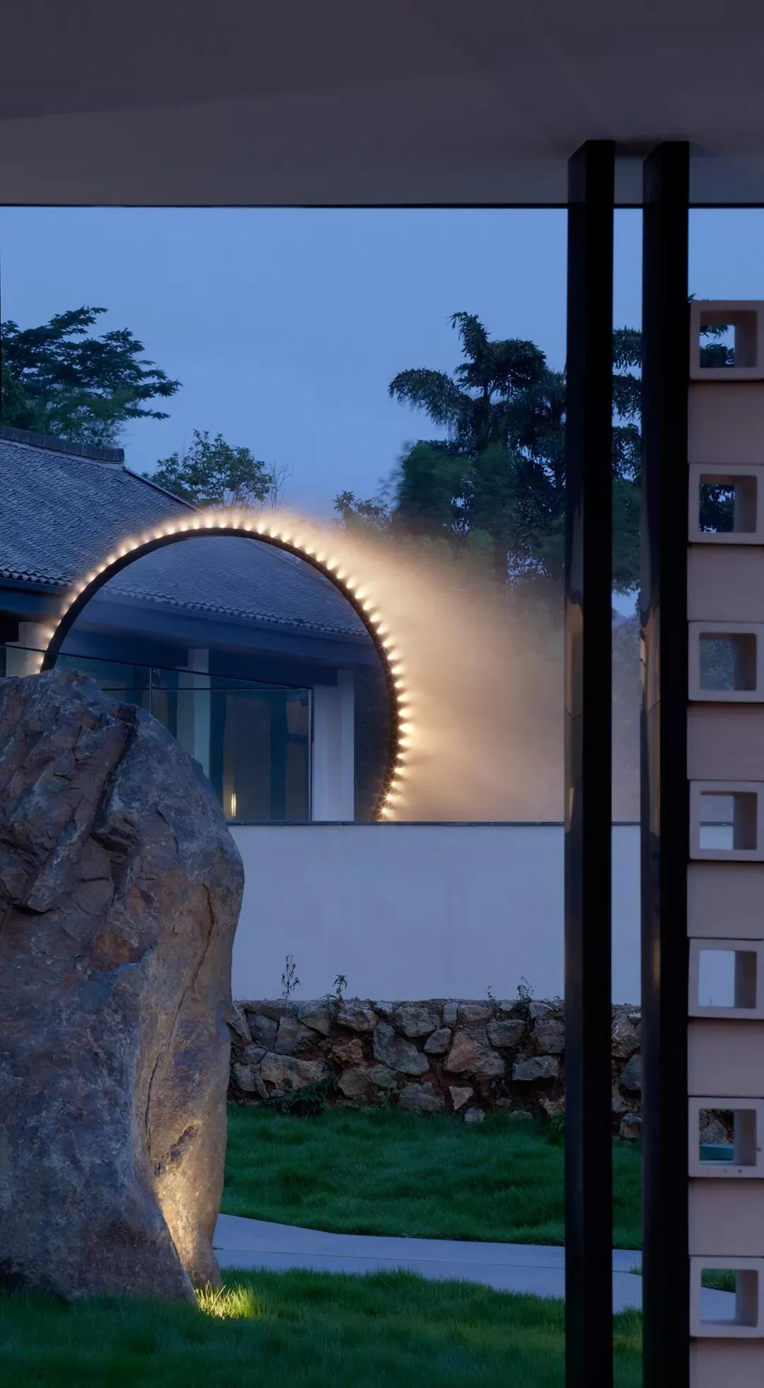 Modern architectural design featuring a concrete arch with integrated lighting at dusk