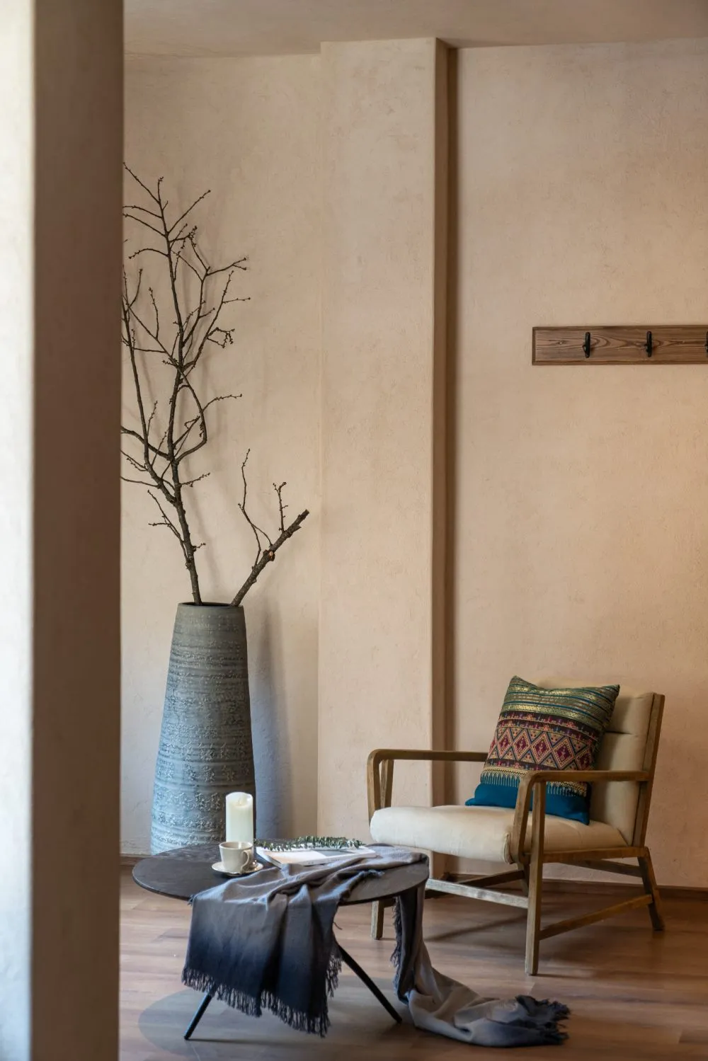 A modern living room featuring a comfortable upholstered chair with a cushioned seat, a round table covered with a grey fring