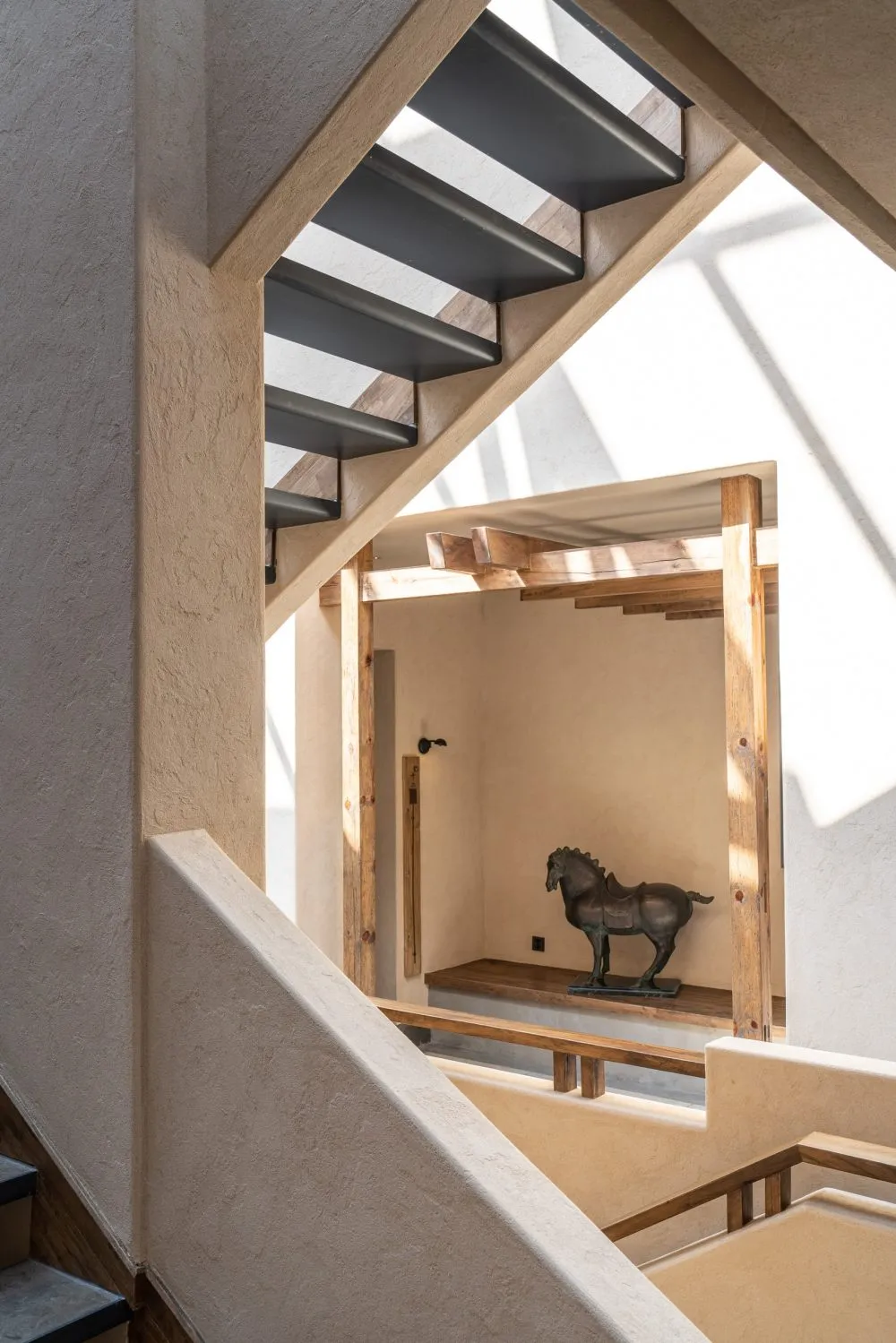 Industrial-style staircase with concrete steps and steel railings, featuring an abstract sculpture of a horse in the backgrou