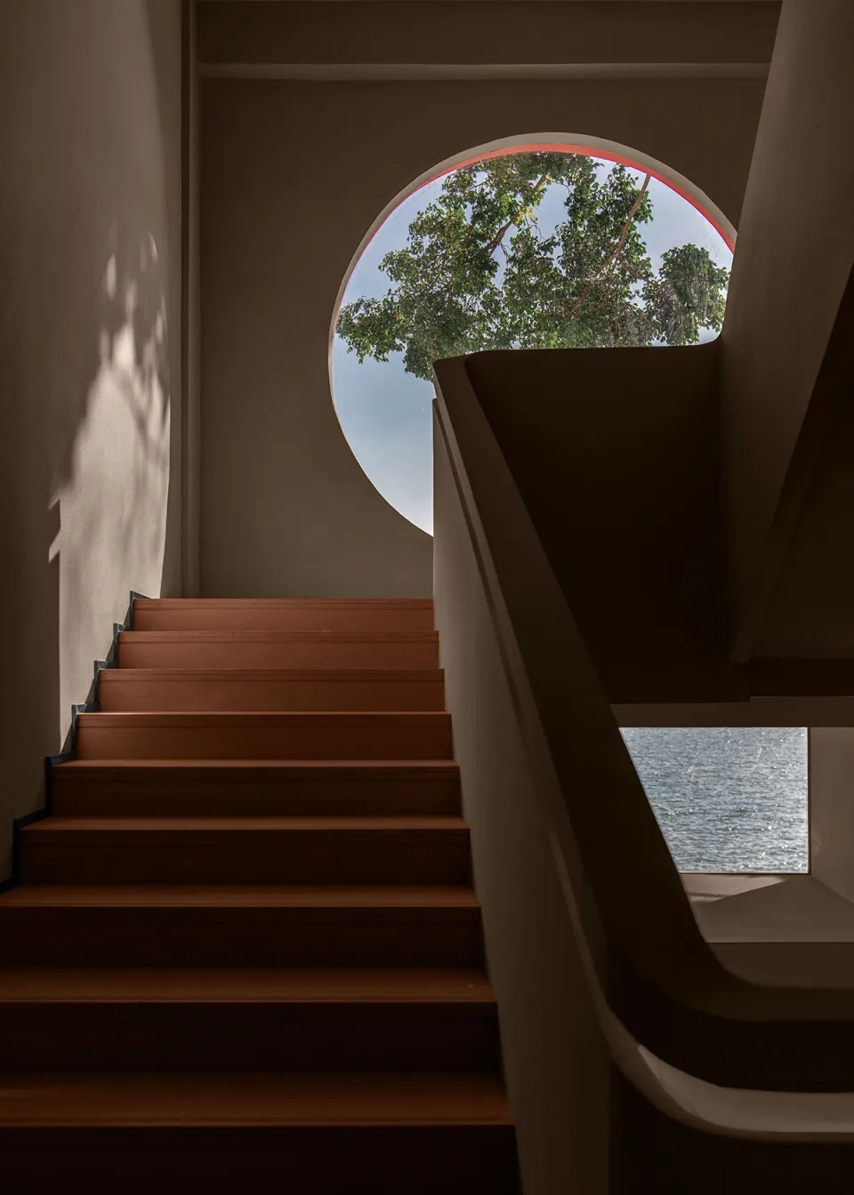 A staircase leading to a garden view through a circular window.