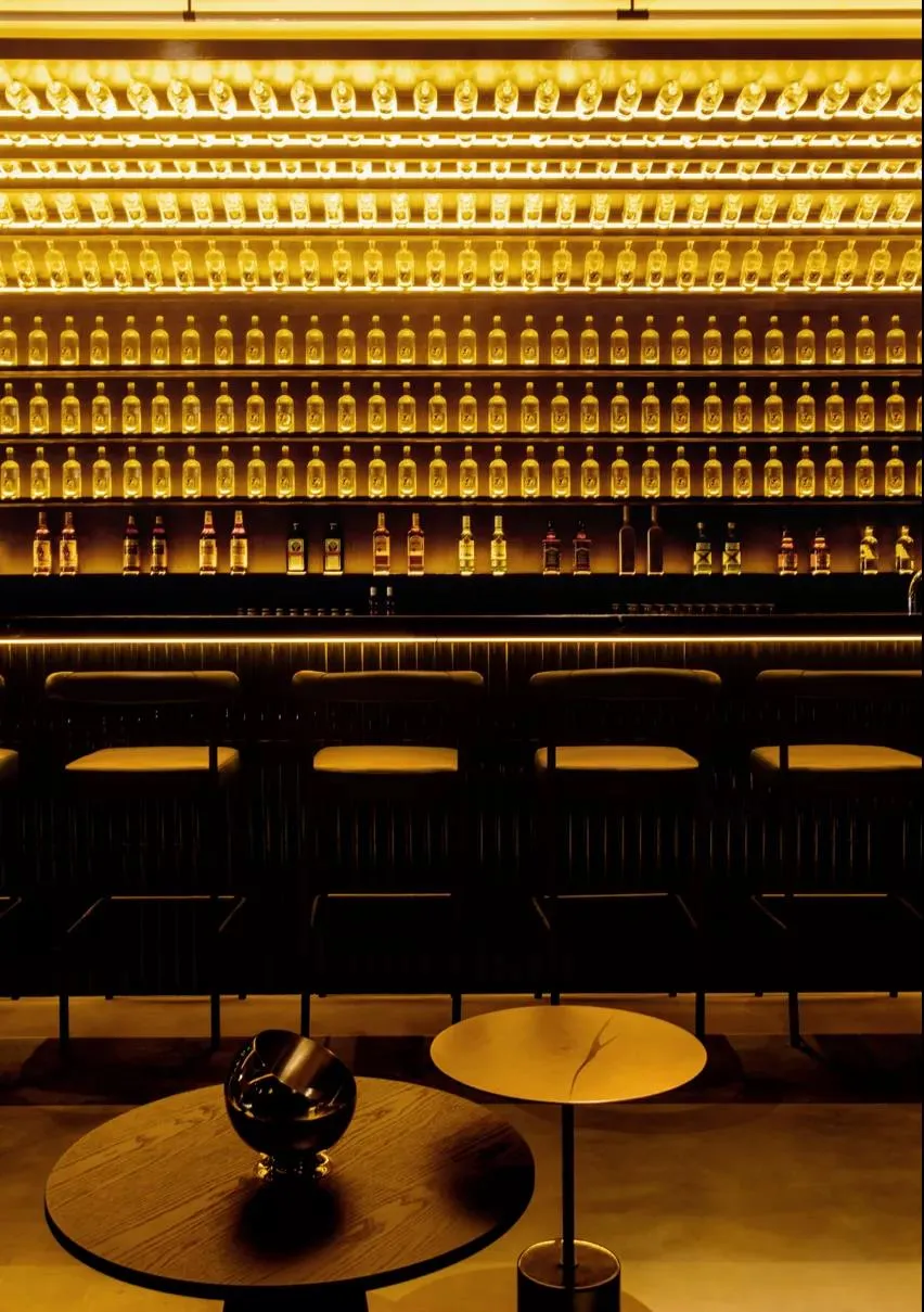 A modern bar interior with metallic shelving displaying various bottles of alcohol.