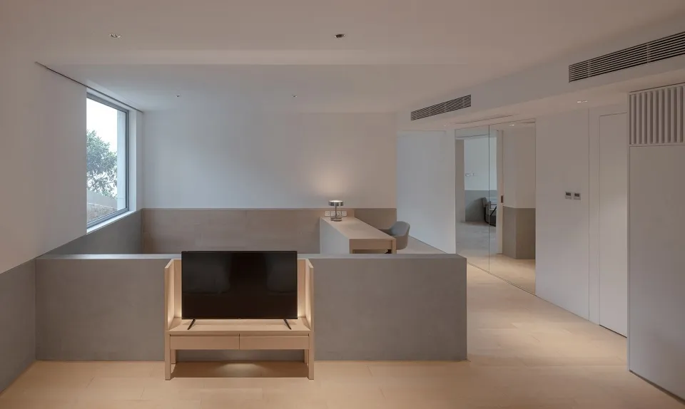 A modern interior living room with concrete flooring, minimalist furniture, and a large window.